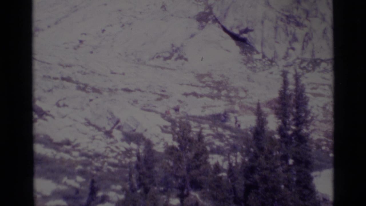 1975 8mm view of snow-covered alpine slopes and evergreen trees in the Minaret Wilderness area of California.