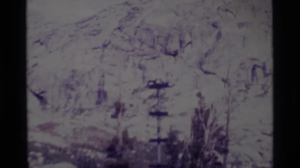 Minaret Wilderness frame with snow, rocky slope, trees, and a tall metal pole structure in soft 8mm color.