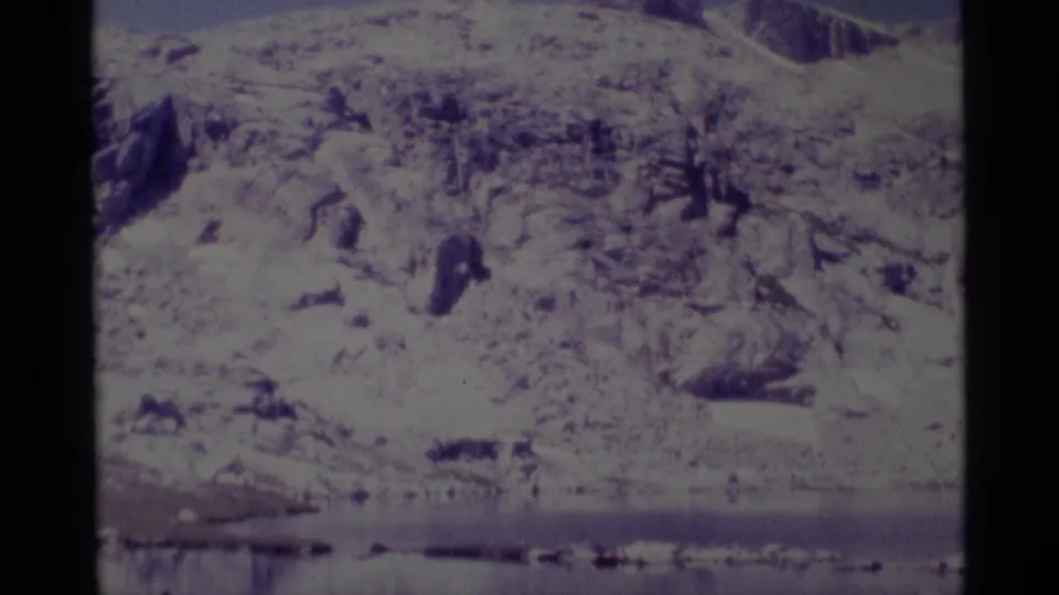 Wide 1975 8mm landscape view of reservoir water and pale rocky slopes in the Minaret Wilderness area.