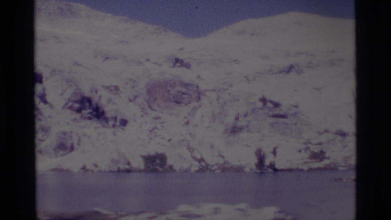 Snowy Sierra Nevada terrain and a calm lake appear in a faded 1975 home-movie frame from Minaret Wilderness.