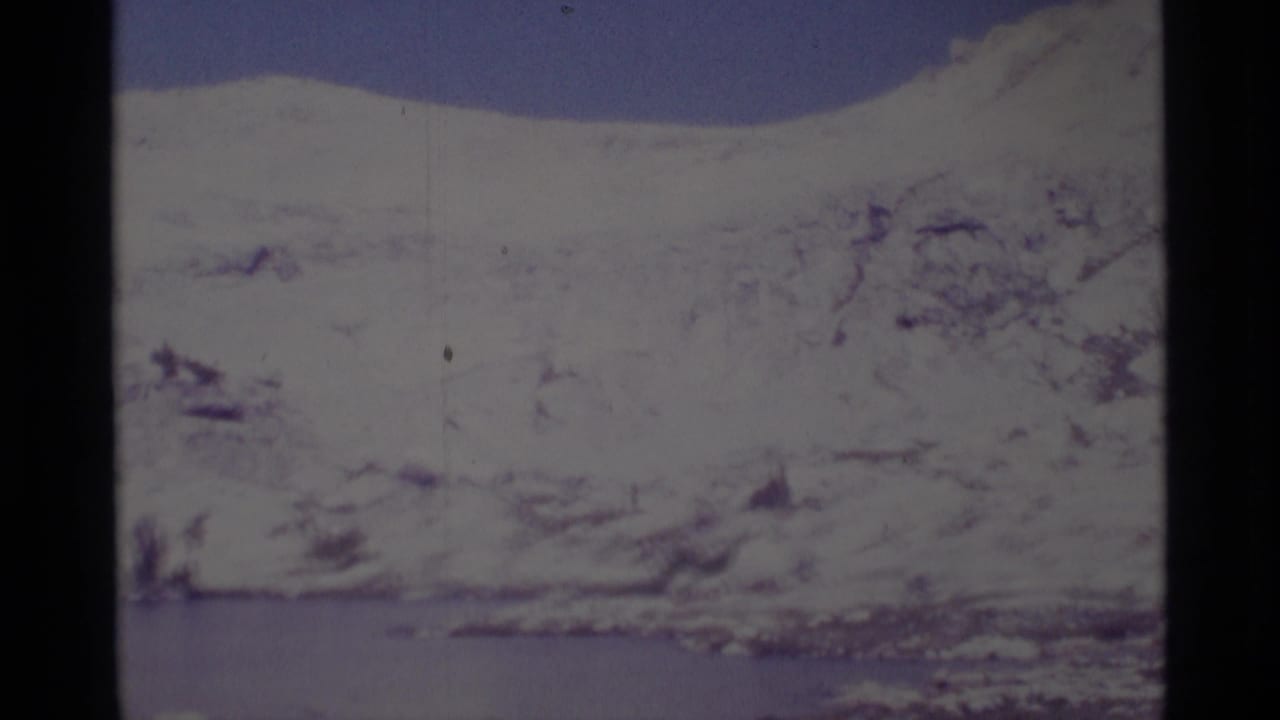 1975 8mm view of snow-covered mountains and a lake in the Minaret Wilderness, with soft focus and visible film wear.
