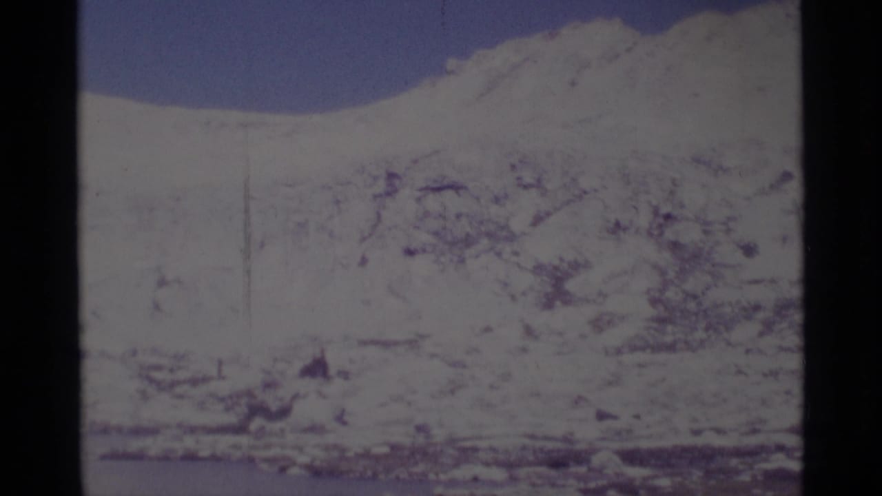 Distant snow-covered peaks and lake surface framed by 8mm film borders.
