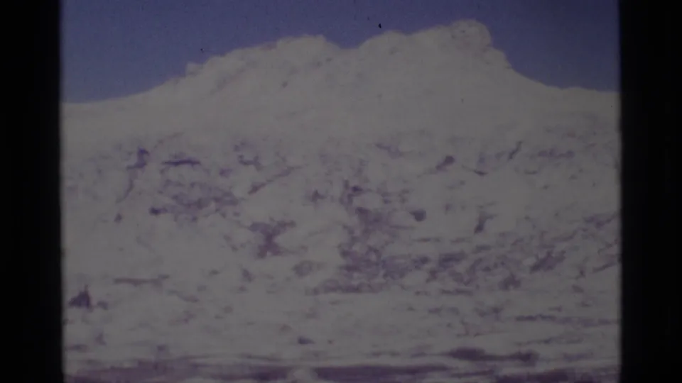 1975 8mm frame of a snow-covered alpine slope and lake in California's Minaret Wilderness, softened by home-movie exposure.