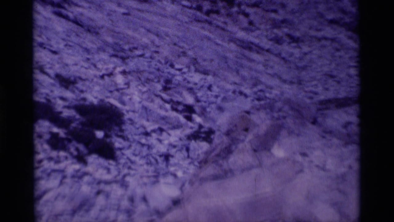 Rocky slope with loose stones and purple-blue film color shift.