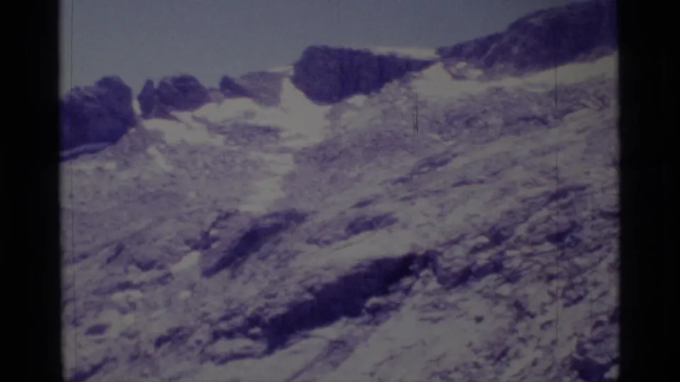 1975 8mm view in Minaret Wilderness showing rough alpine rock, scattered snow, and dark ridgeline outcrops.