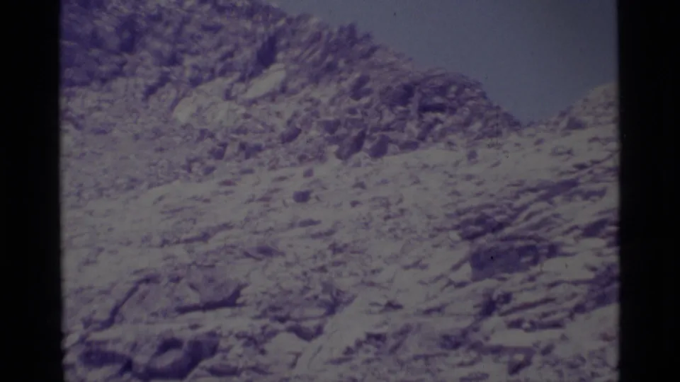Aged 8mm frame of a jagged Minaret Wilderness hillside, with purple-blue color cast and no visible people or structures.