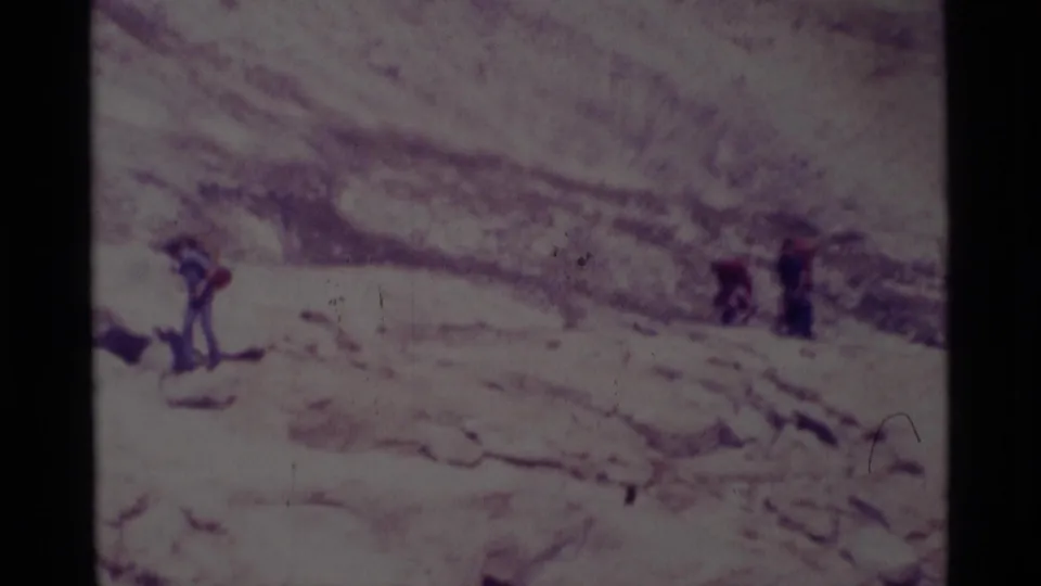 A 1975 Minaret Wilderness frame shows hikers spaced across a rocky snowfield, their figures small against the mountain terrain.