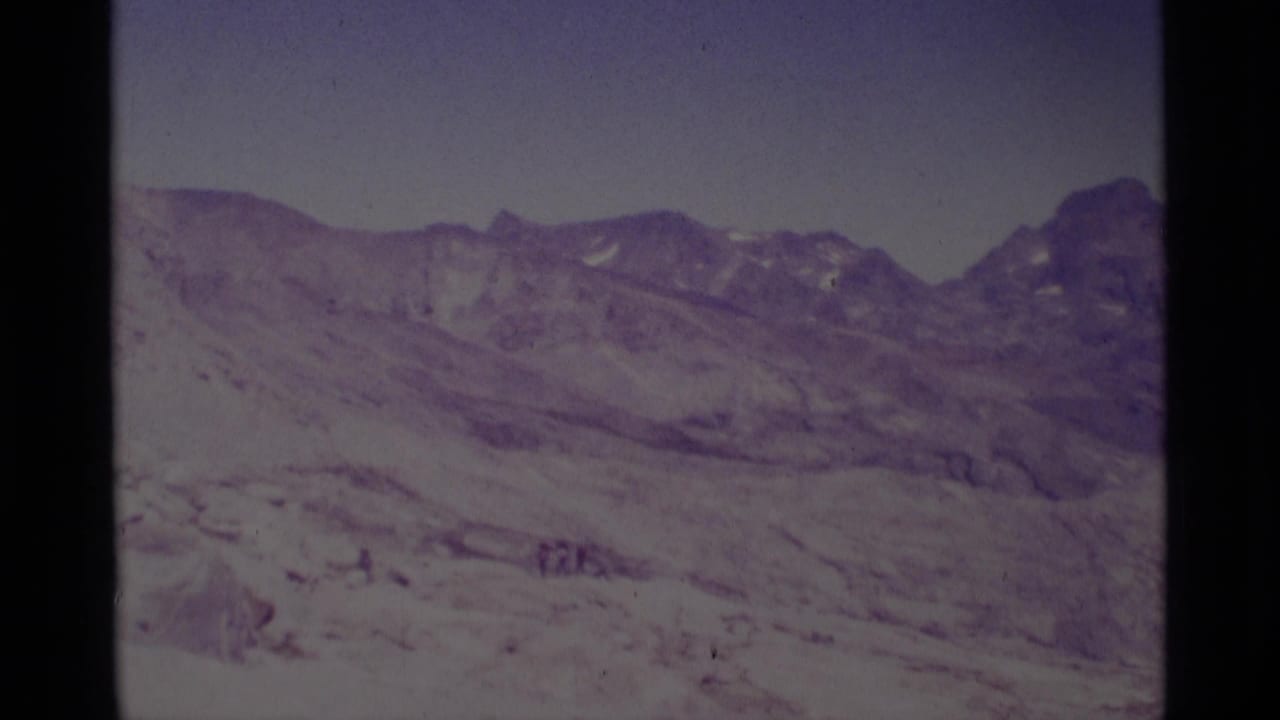 Minaret Wilderness landscape on 8mm film, showing a broad snow-covered basin, rocky ridge, and faint distant figures.