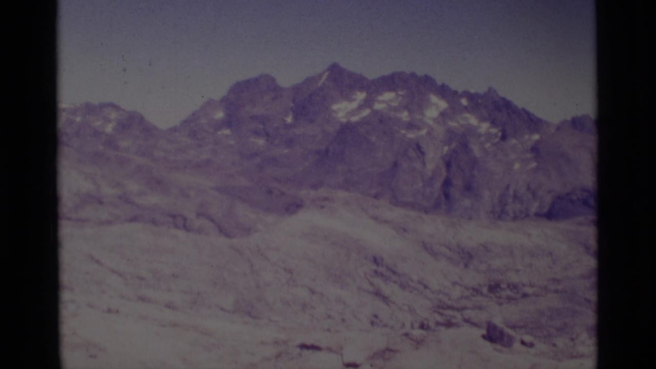Mountain ridge and pale rocky slope framed by dark vertical film borders.