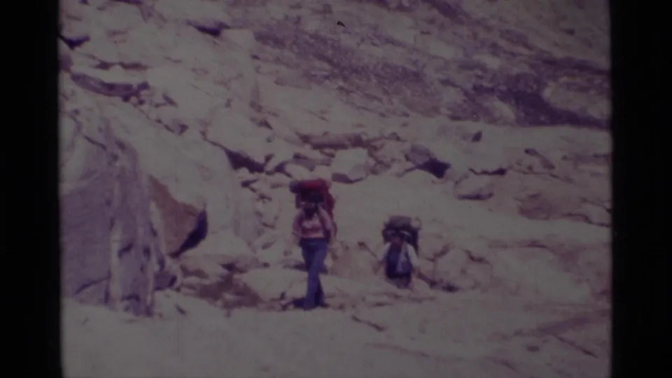 Distant backpackers traverse rocky high-country terrain in Minaret Wilderness, California, in 1975 home-movie footage.