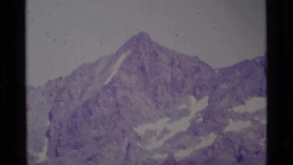 1975 Minaret Wilderness view of a rugged alpine peak with scattered snow patches, seen through faded 8mm color.