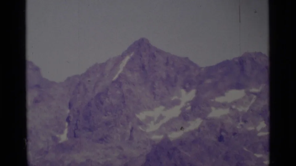 1975 Minaret Wilderness frame showing a broad rocky alpine face with scattered snow and soft, faded 8mm exposure.