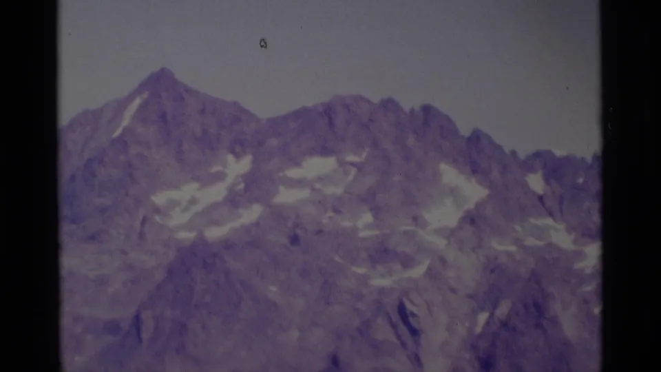 1975 Minaret Wilderness mountain vista with jagged ridge lines, patches of snow, and visible 8mm film texture.