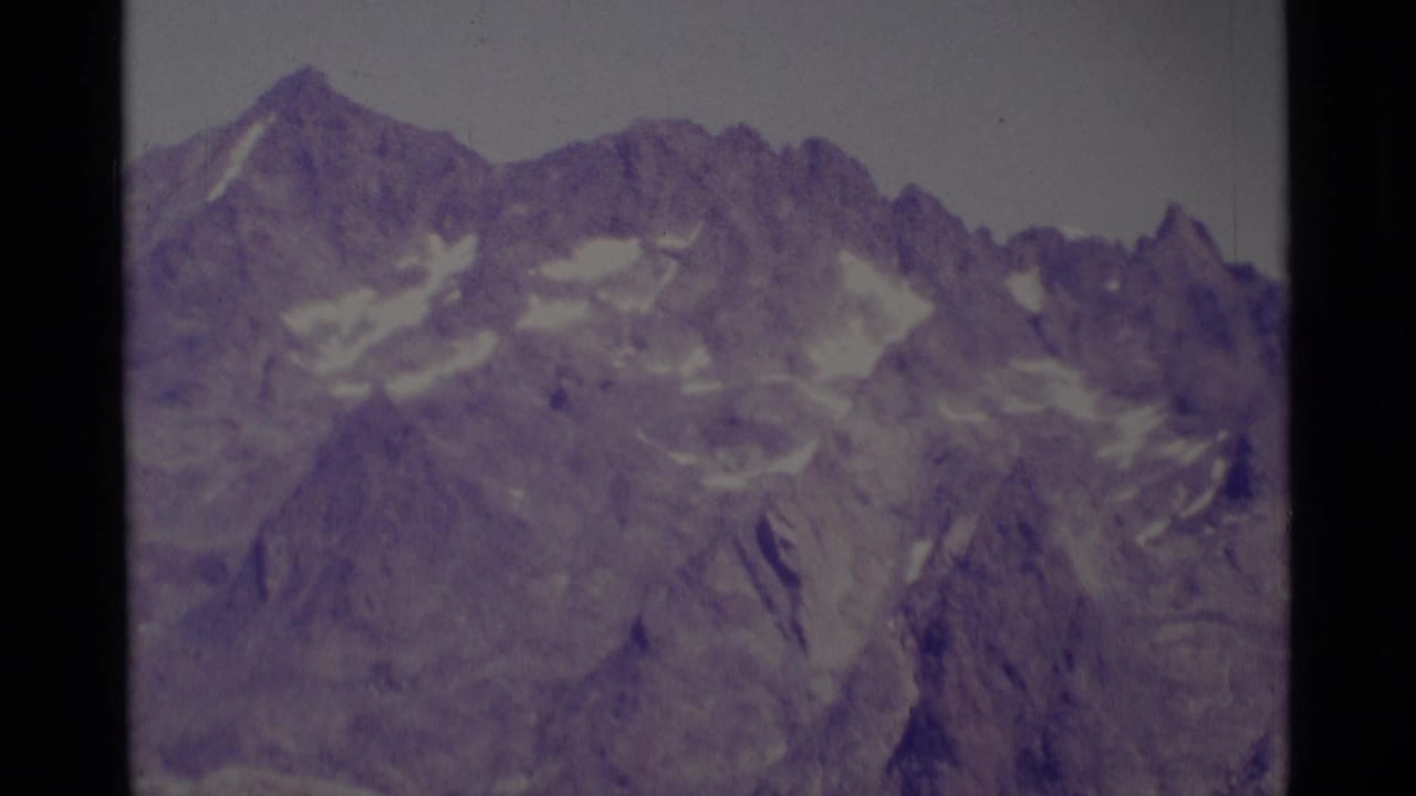 Jagged mountain peaks with snow patches under a pale sky.