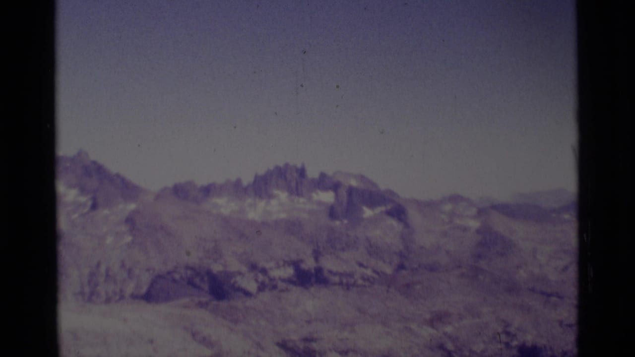 1975 8mm view of the Minaret Wilderness area, showing distant jagged Sierra Nevada peaks and muted snow patches under a pale sky.