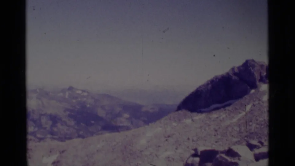 1975 Minaret Wilderness mountain view across a rocky slope toward distant ridges beneath a pale sky.