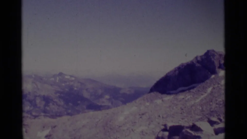 1975 8mm Minaret Wilderness view with a pale rocky slope, dark peak, distant ridges, and aged film color.