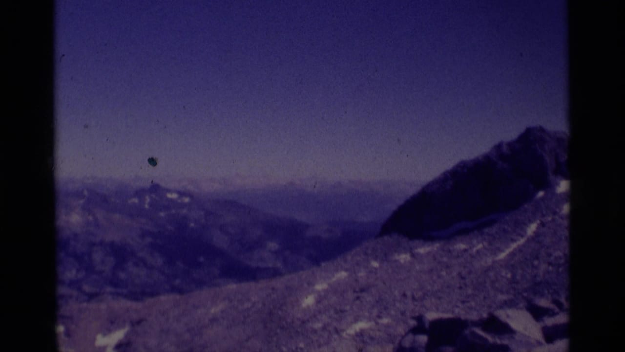 Distant mountain ridges and a dark rocky peak seen across a barren slope.