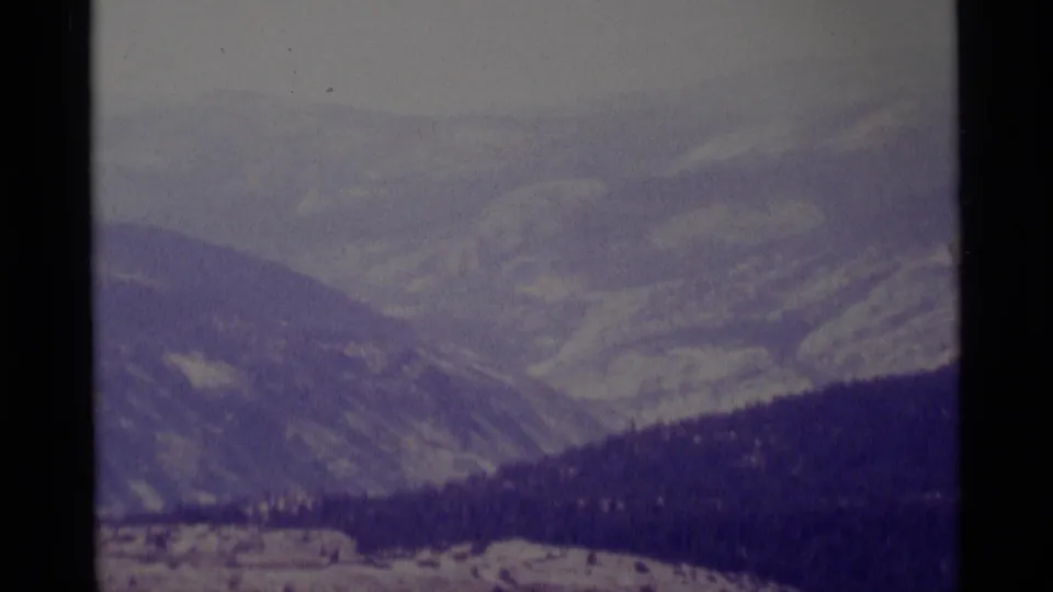 8mm view of layered mountain terrain in the Minaret Wilderness area, with forested slopes under a hazy sky.