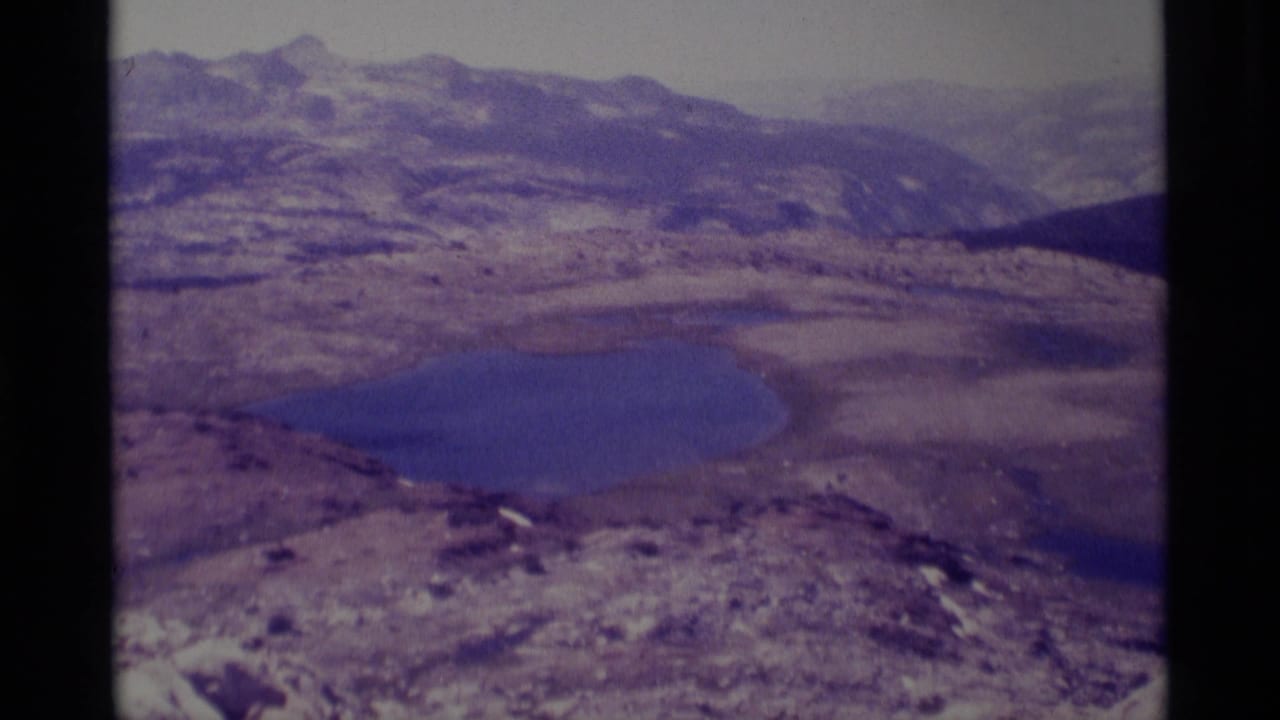 Mountain lake and surrounding ridges viewed through a soft, grainy 8mm frame.