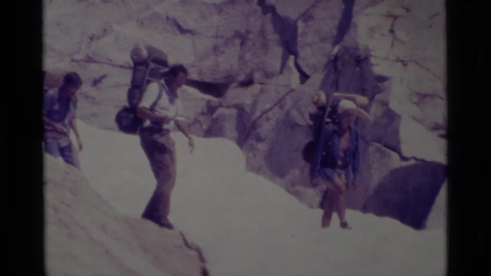 A small hiking group with packs negotiates a rocky descent in California's Minaret Wilderness, filmed on 8mm in 1975.