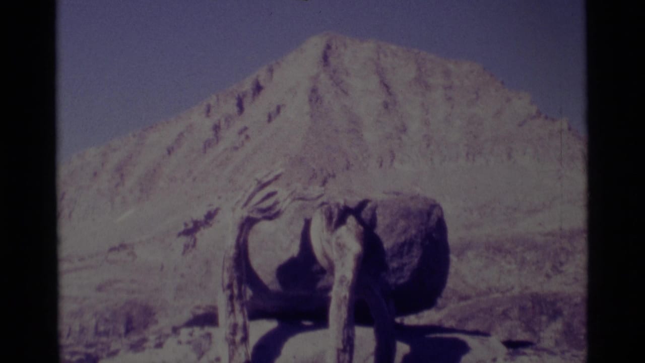 1975 Minaret Wilderness home-movie frame with a rough wooden foreground object and a faded mountain backdrop.