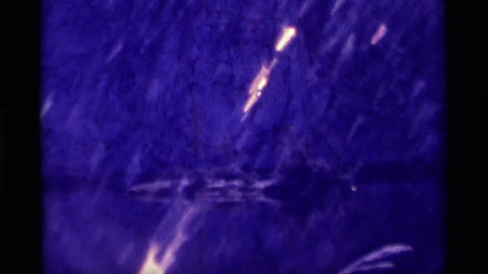 A handheld 8mm view of dark wilderness brush and reflective water, with bright exposure streaks and a strong purple film cast.