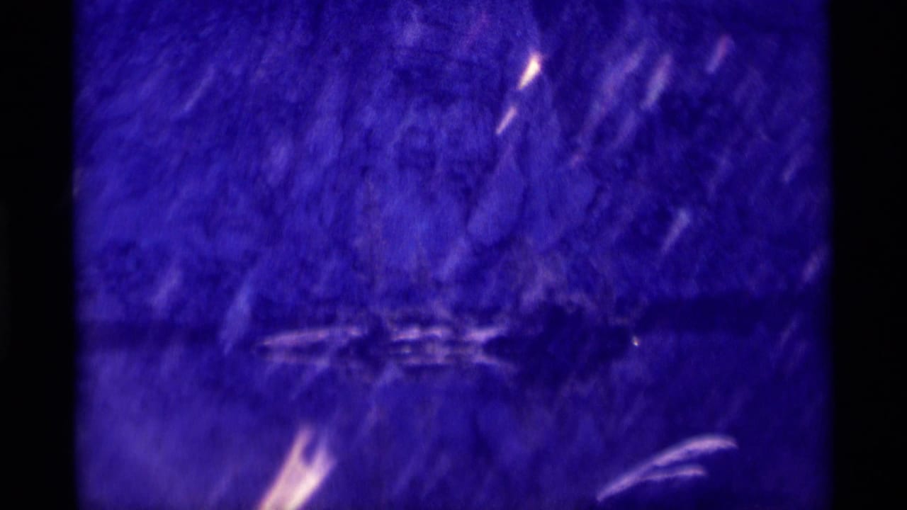 Dark blue cave-like surface with faint pale streaks and film scratches.
