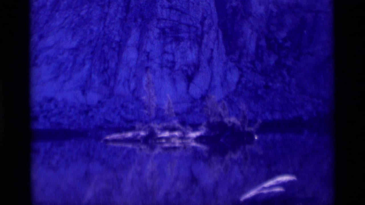 Blue-purple 8mm view of a rocky cliff reflected across calm water, consistent with the Minaret Wilderness location metadata.