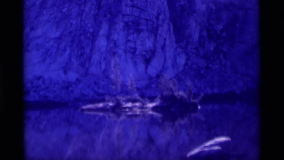 Blue-purple 8mm view of a rocky cliff reflected across calm water, consistent with the Minaret Wilderness location metadata.