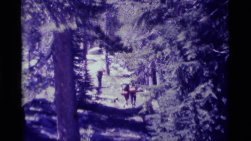 Backpackers walk farther along a rocky forest path in the 1975 Minaret Wilderness home-movie scene.