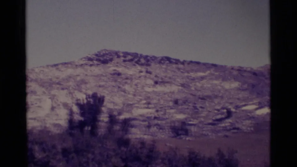 1975 8mm Minaret Wilderness landscape showing a low rocky ridge, sparse brush, and a washed pale sky.