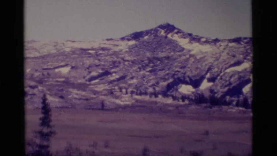 Minaret Wilderness mountain view on 8mm film, showing rocky snow-patched slopes above a muted alpine meadow.