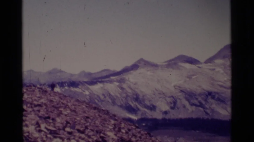 Minaret Wilderness landscape view with rocky foreground, distant peaks, snow patches, and a dark lake or basin below.