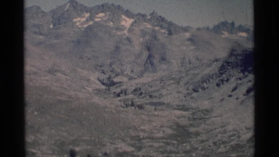 Soft 8mm frame of the Minaret Wilderness landscape, showing pale rocky slopes, distant peaks, and alpine ground cover.