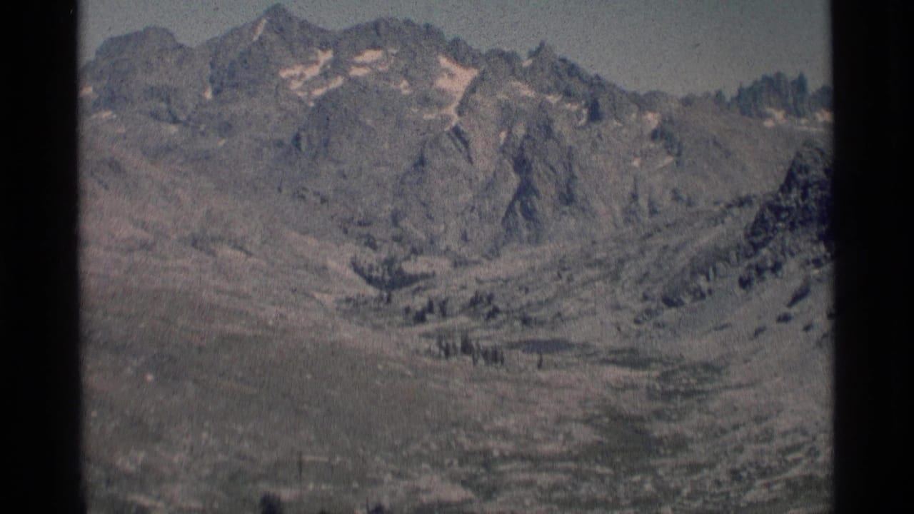 1975 8mm view of rugged Minaret Wilderness peaks with small snow patches above an open alpine valley.