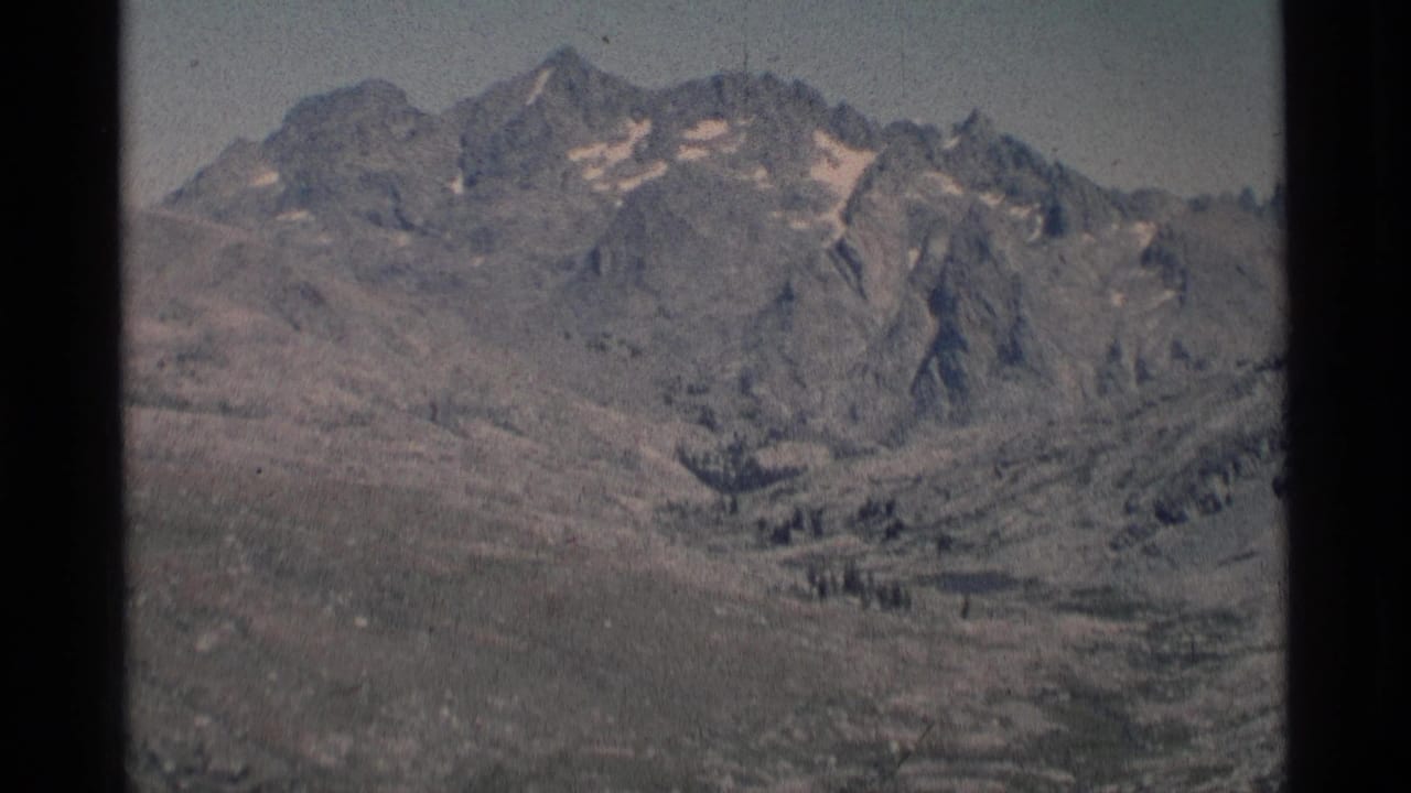 Distant rocky peaks and a high valley with sparse vegetation.
