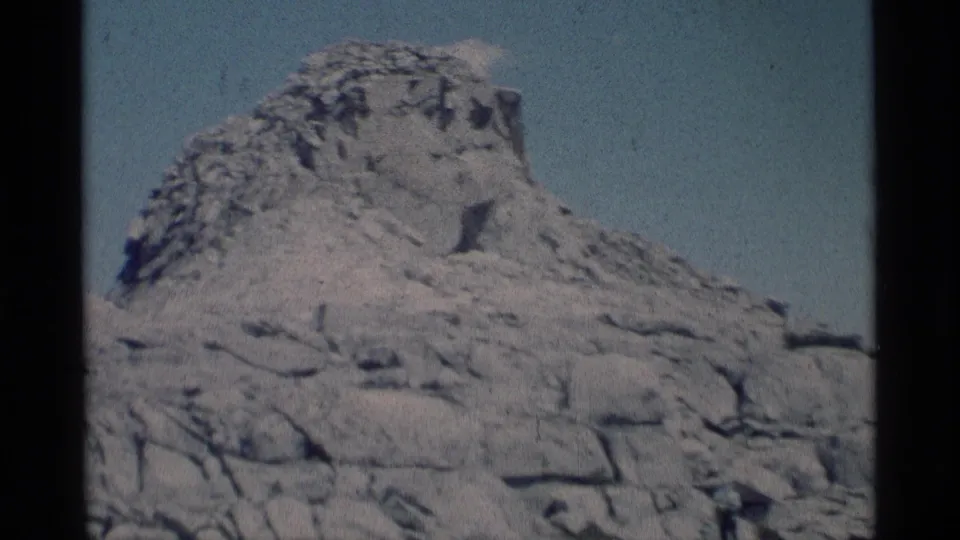 1975 Minaret Wilderness home-movie frame showing a pale rugged rock formation under a clear blue sky.