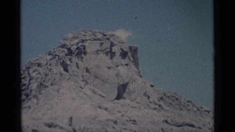8mm wilderness view of a weathered California rock formation with blue sky and a faint cloud above it.