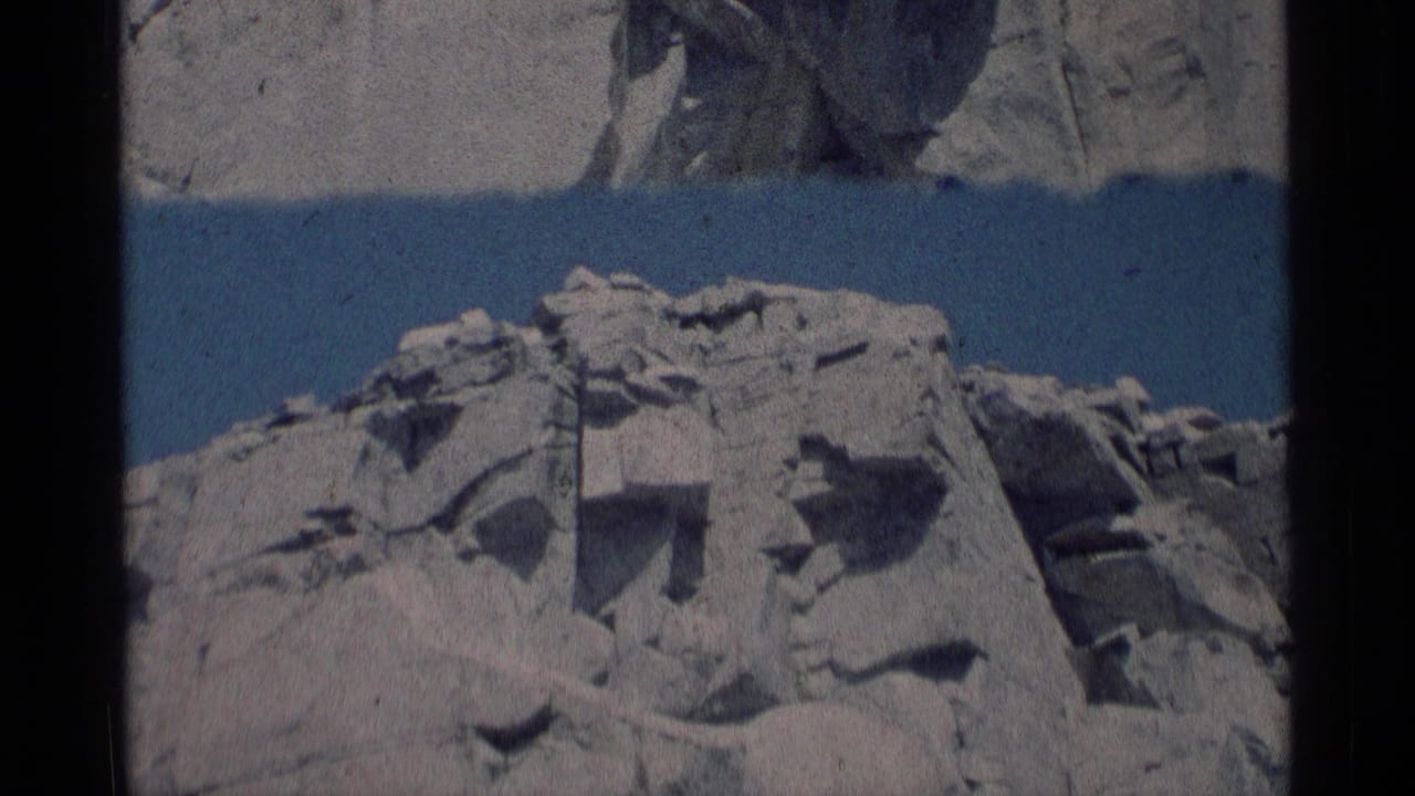 Archival 8mm frame from Minaret Wilderness showing fractured light stone, angular ledges, and clear sky.