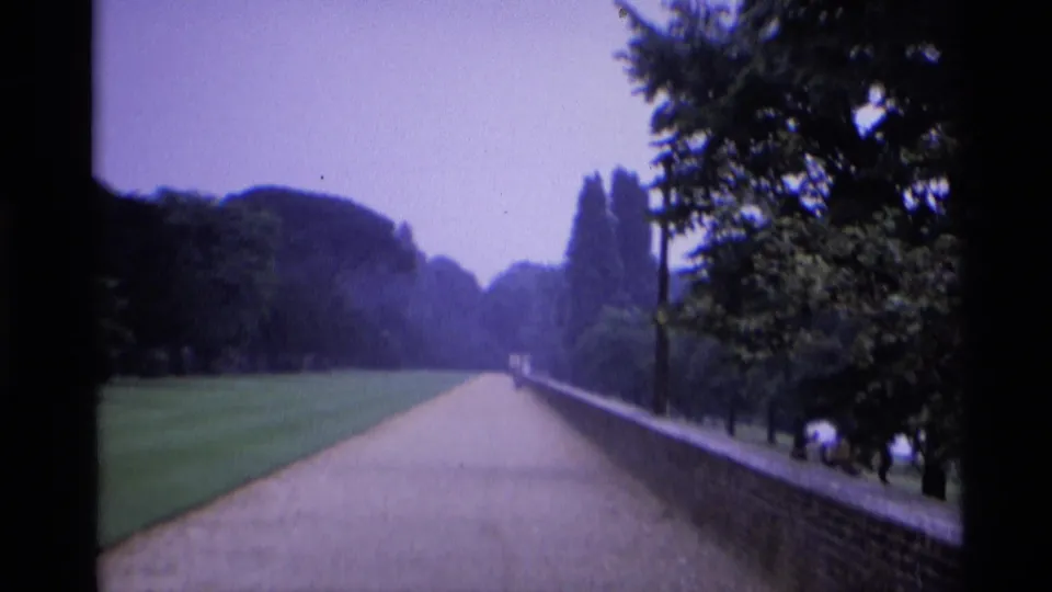 A late-1960s London park view shows the path, brick wall, lawns, trees, distant walkers, and a few people near the right side.