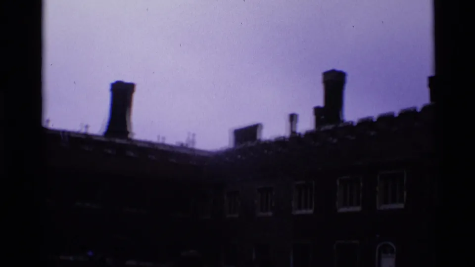 1969 London 8mm frame showing a wide, underexposed view of a long historic facade with crenellations and windows.