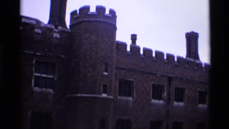 1969 London 8mm frame showing a round tower, crenellated roofline, chimneys, and barred windows on a historic exterior.