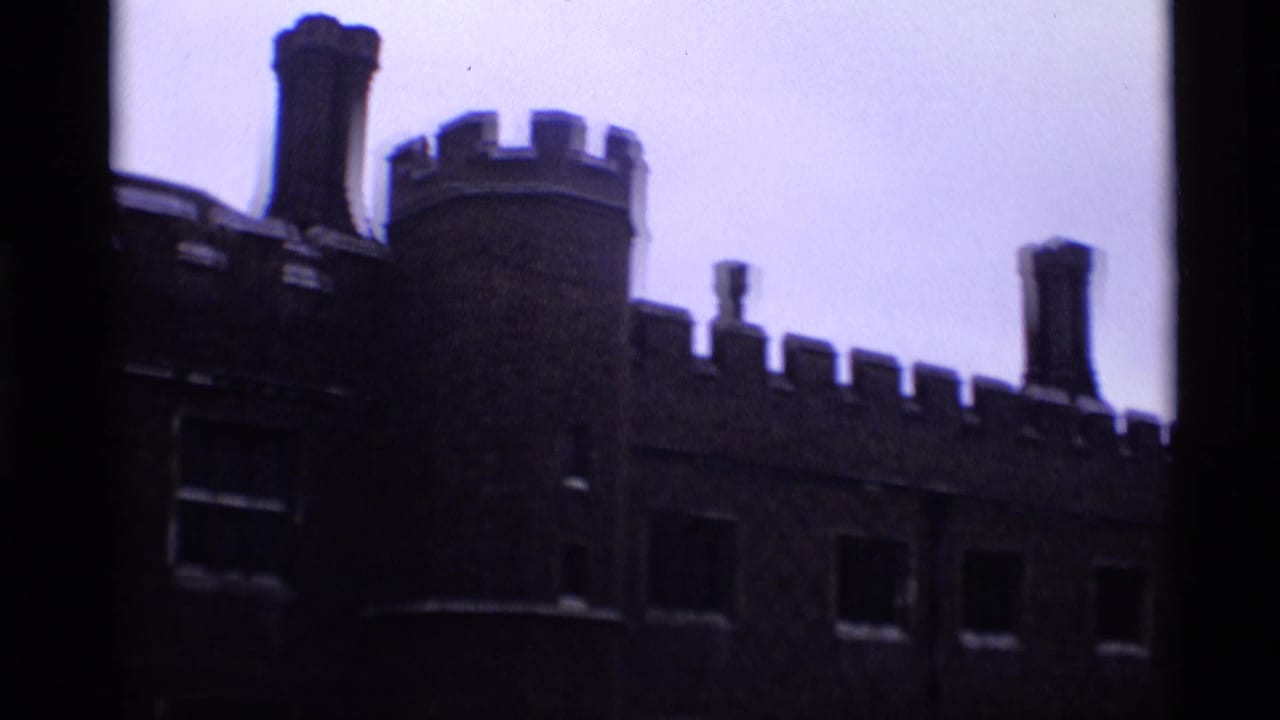 1969 London 8mm frame showing a dark crenellated exterior wall, round tower, chimneys, and pale sky.