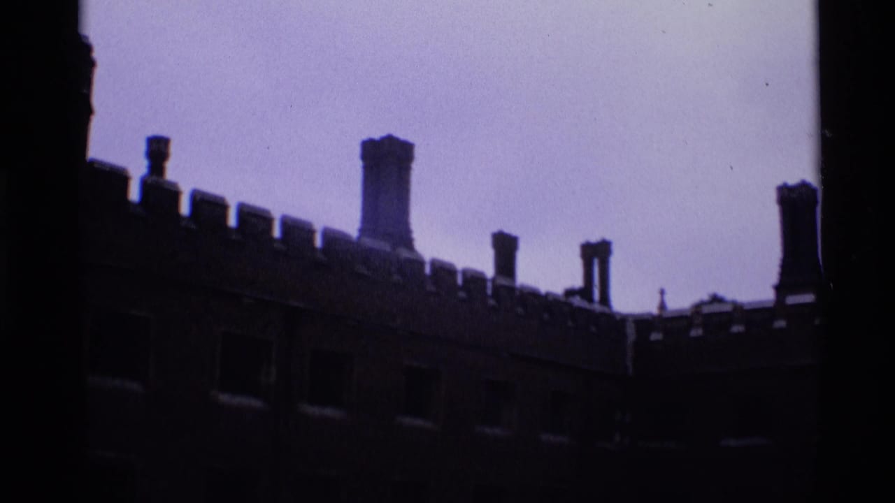 Long dark castle-style wall with battlements and chimneys under a pale sky.