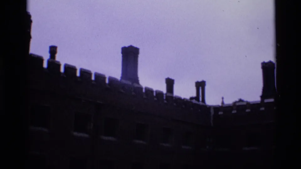 1969 London 8mm view along a dark historic-looking wall with battlements, chimneys, and recessed windows.