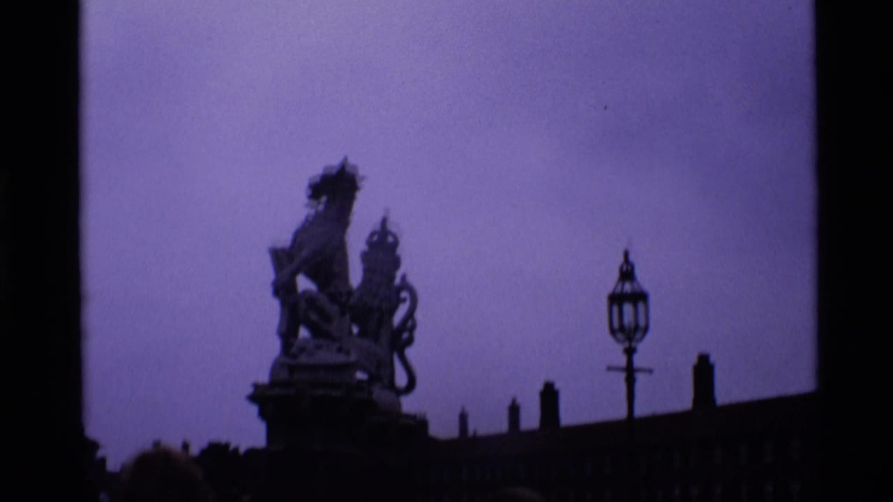 1969 London frame with a dark silhouetted statue or monument, roofline, lamp-like fixture, and purple shifted sky.