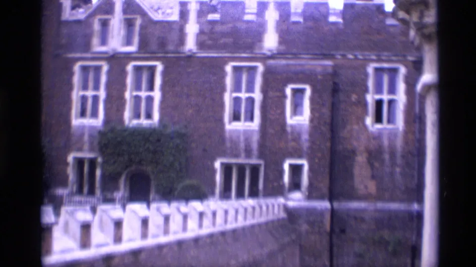 1969 London exterior showing a brick historic facade, tall windows, white railings, greenery, and an arched entrance area.