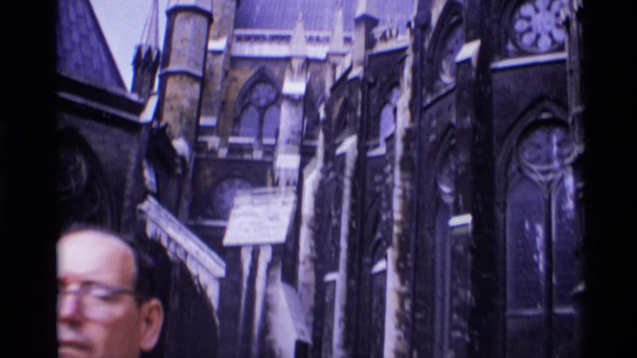 1969 London home-movie frame with a partial adult face crossing the foreground before ornate Gothic cathedral stonework.