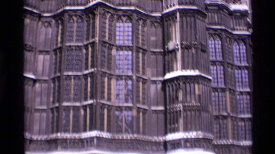 1969 London 8mm frame showing close Gothic stonework, tall windows, and ornate facade details on a historic exterior.